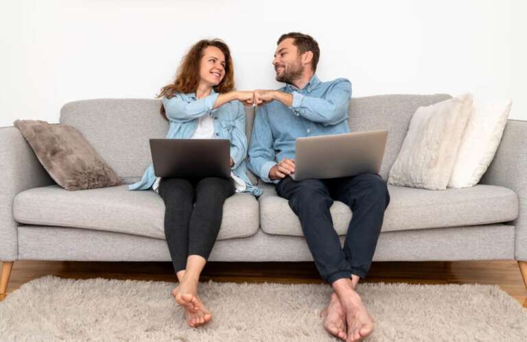Couple working on laptops at home and fist bumping