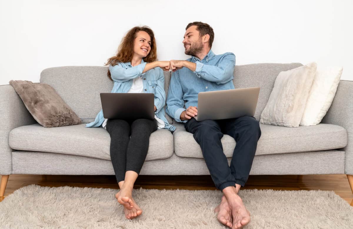 Couple working on laptops at home and fist bumping
